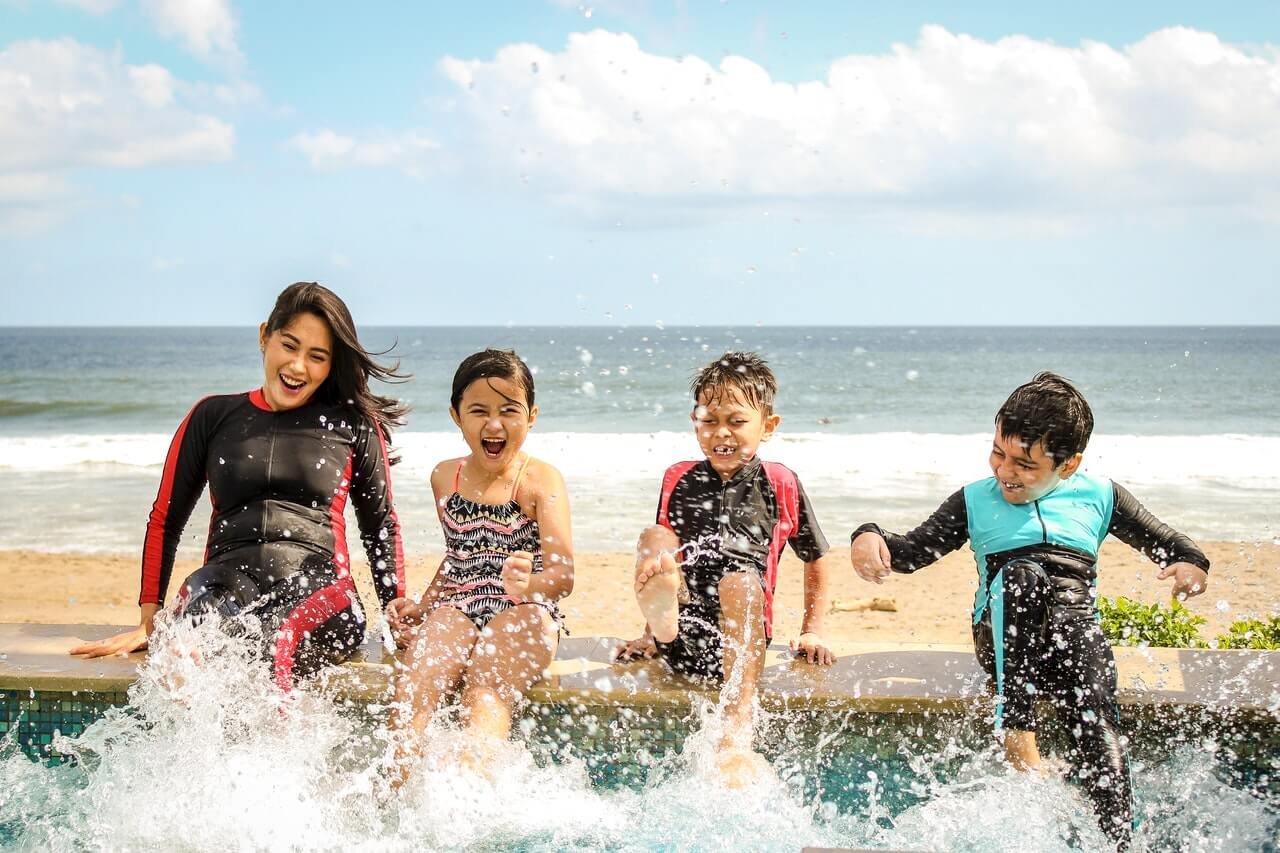 4 crianças brincando com os pés na água da piscina